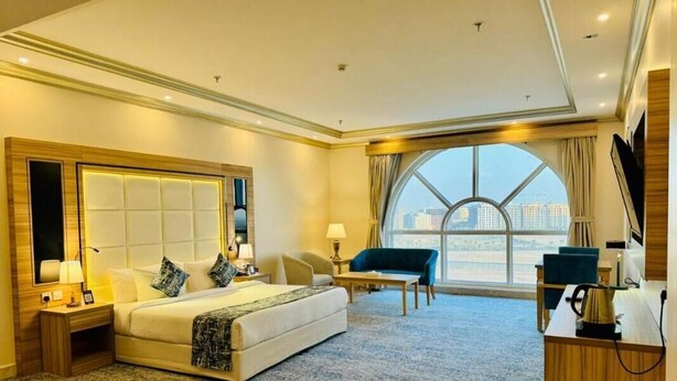 Une chambre d’hôtel avec un grand lit, un bureau, une chaise et une vue sur la ville grâce à une grande fenêtre.