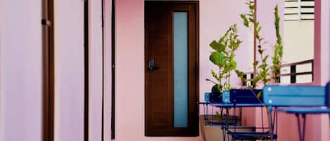 Un pasillo con una puerta, suelo de baldosas y una planta.