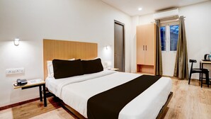 Une chambre d’hôtel comprenant un lit, une table de chevet, une lampe, une armoire et un bureau avec une chaise.