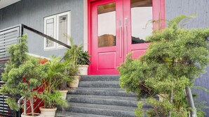 Un bâtiment avec une porte rouge vif, un escalier et des plantes en pot.