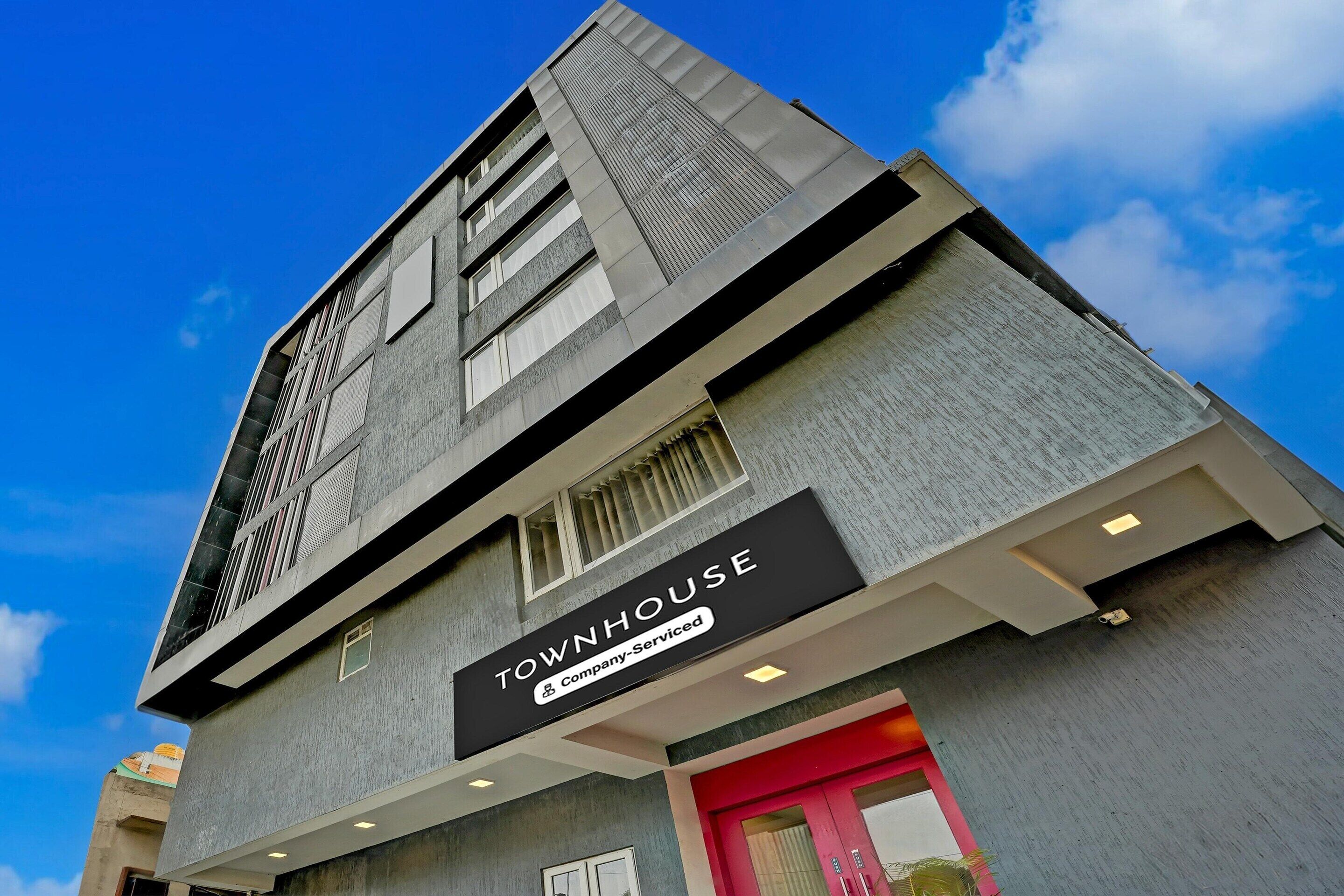 A modern building with a sign reading "TOWNHOUSE & Company Serviced."
