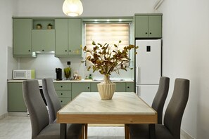 Enjoy meals at the dining table with four chairs, a vase with flowers, and a refrigerator nearby.