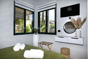 Relax in this serene bedroom with a large bed, flat-screen TV, and a view of the surrounding residential area.