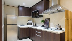 A modern kitchen with dark wooden cabinets, a stainless steel refrigerator, a microwave, a gas stove, and a coffee maker.