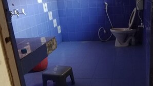 Un bany petit amb terra de rajola blava, un vàter, un lavabo i un petit tamboret.