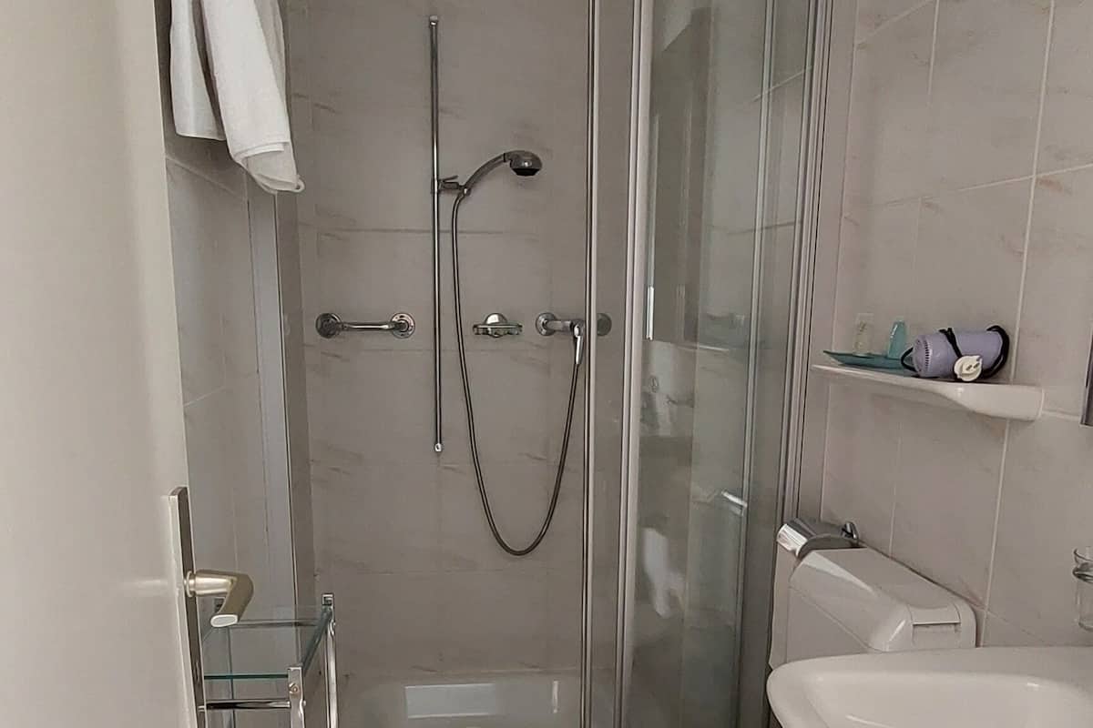Um banheiro moderno com chuveiro em gabinete de vidro, vaso sanitário branco e toucador com pia.
