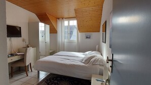 A bedroom with a bed, a desk, and a chair. There is a window with curtains and a picture on the wall. - Le Bélimont Panorama (Belmont-sur-Lausanne)