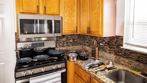 A kitchen with wooden cabinets, a stainless steel stove, a microwave, and granite countertops. - Serene 5-Bedroom Retreat, Oswego (Oswego)
