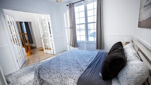 A bedroom with a bed, a window with curtains, a door, and a view of the outside. - Serene 5-Bedroom Retreat, Oswego (Oswego)