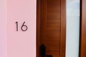 A door with a wooden panel and a black handle. - Room 16: Grand King Suite w/ Desk & Sofa Bed (San Juan)