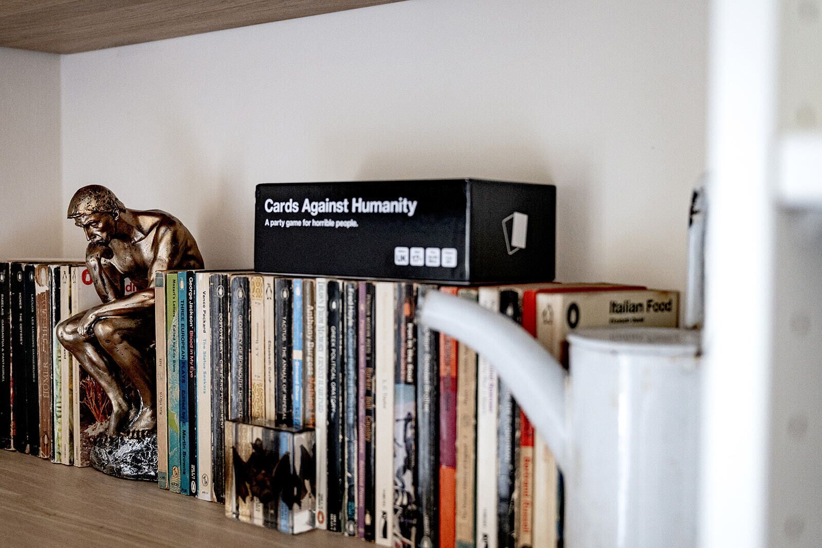 Una libreria con una varietà di libri e una statua di un uomo pensieroso.