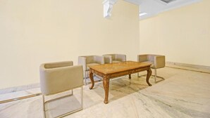 A conference room with a marble floor, a wooden table, and four beige chairs.