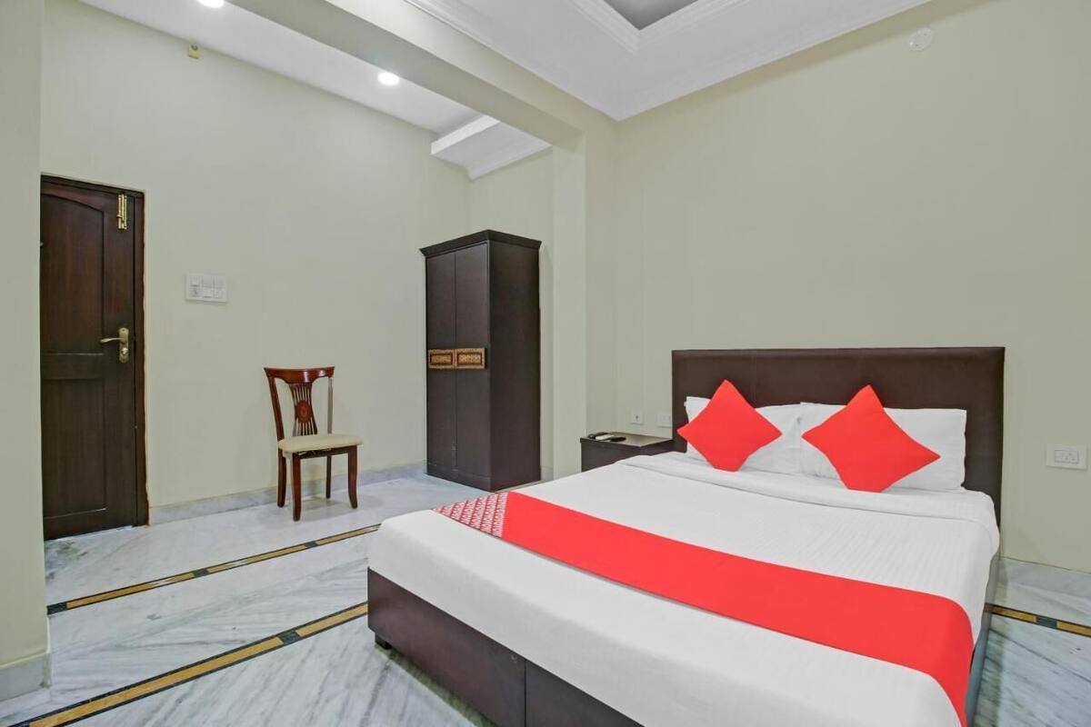 Una habitación de hotel con una cama grande, un armario de madera, una silla y una puerta.