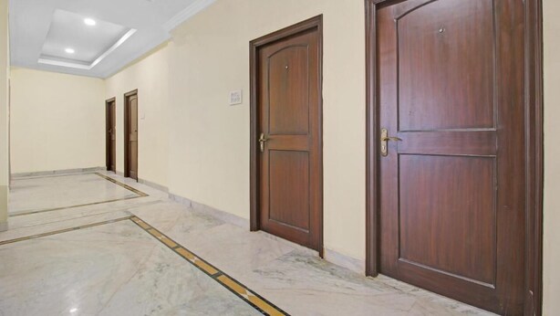 A hallway with marble flooring and wooden doors.