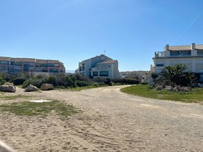 A gravel path leading to a modern building with a flat roof and large windows. - Seafront apartment with terrace and pool (Saint-Cyprien)