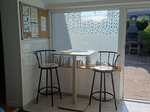 A small kitchen with two bar stools, a table, and a window with frosted glass.