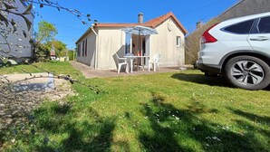 Une maison avec un patio, une voiture garée devant, et un ciel bleu dégagé.