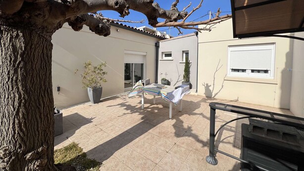 A patio area with a pergola, potted plants, a table, and a chair. - Single-storey house with air conditioning, 3 bedrooms, near the beach (Valras-Plage)