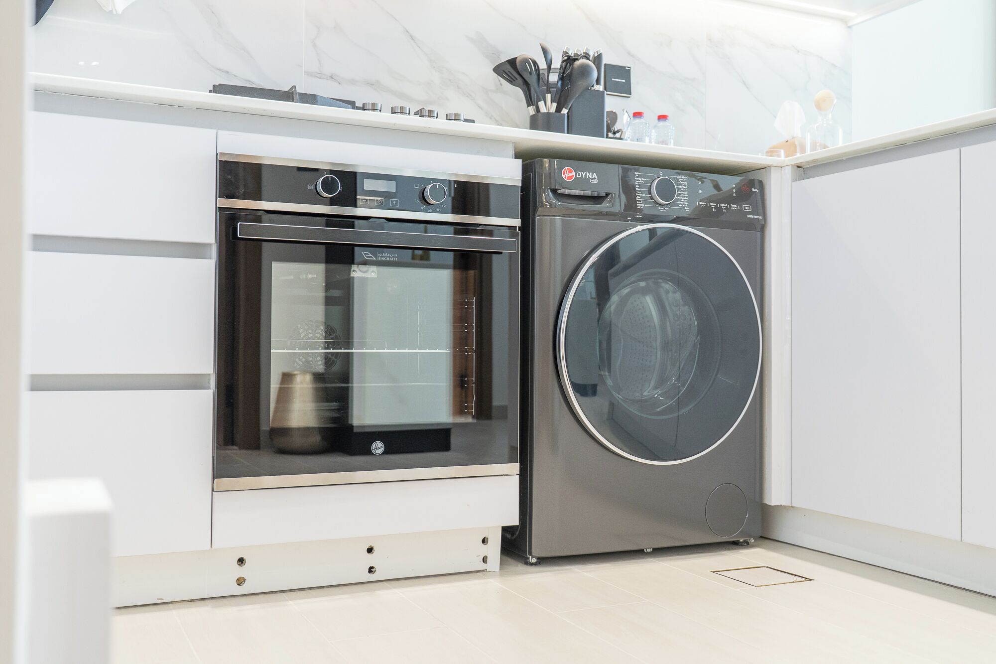 Une cuisine compacte dotée d’un four encastré et d’un lave-linge à chargement frontal.