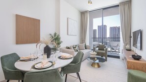 Ein modernes Wohnzimmer mit Essbereich, großen Fenstern mit Blick auf die Stadt, einem Flachbildfernseher und einer minimalistischen Einrichtung.