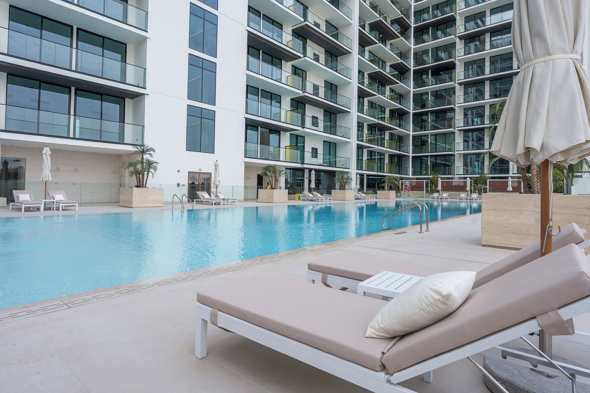 Un hotel moderno con una grande piscina interna, numerosi balconi e lettini prendisole.