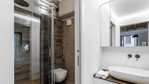 A modern bathroom with a glass-enclosed shower, a white sink, and a toilet.