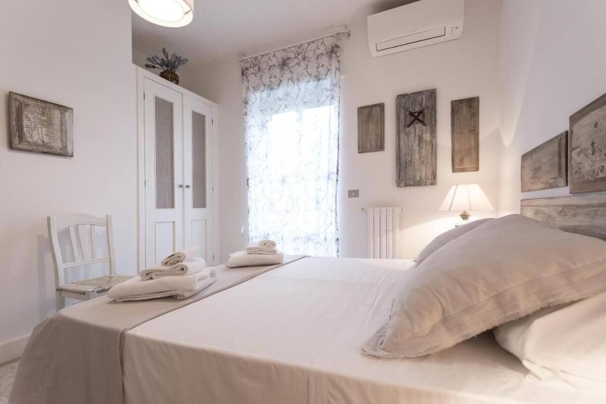 A bedroom with a bed, a chair, a radiator, and a window with curtains.