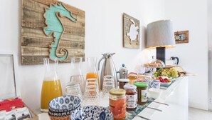 A breakfast bar with various food items and drinks, a coffee maker, and decorative wall art. - Bòmera Rooms (Gallipoli)