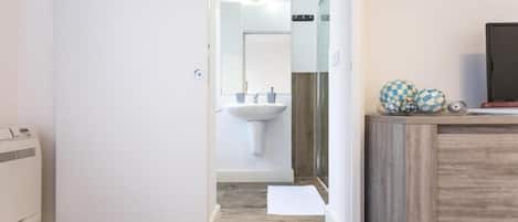 Un baño moderno con un lavabo blanco, espejo y tocador de madera.