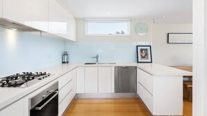 A modern kitchen with white cabinets, a stainless steel stove, and a dishwasher.