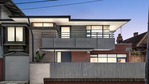 A modern two-story house with a balcony, large windows, and a garage.