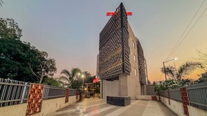 A modern building with a unique facade, a paved walkway, and a metal fence. - Zip By Spree Hotels Chinchwad (Pimpri - Chinchwad)