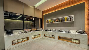 A buffet setup with various food containers and utensils, a marble countertop, and a brick accent wall. - Zip By Spree Hotels Chinchwad (Pimpri - Chinchwad)