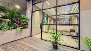 A modern interior with a reception area, glass doors, and potted plants. - Zip By Spree Hotels Chinchwad (Pimpri - Chinchwad)
