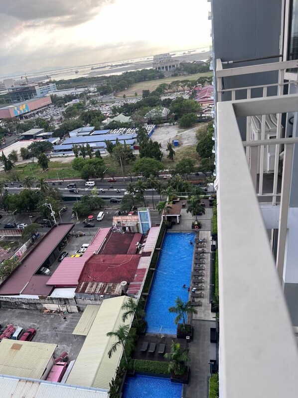 A high-rise building with a view of a swimming pool, a parking area, and surrounding buildings.