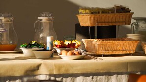 Montaje de un bufé de desayuno con diferentes alimentos, una jarra y cestas.