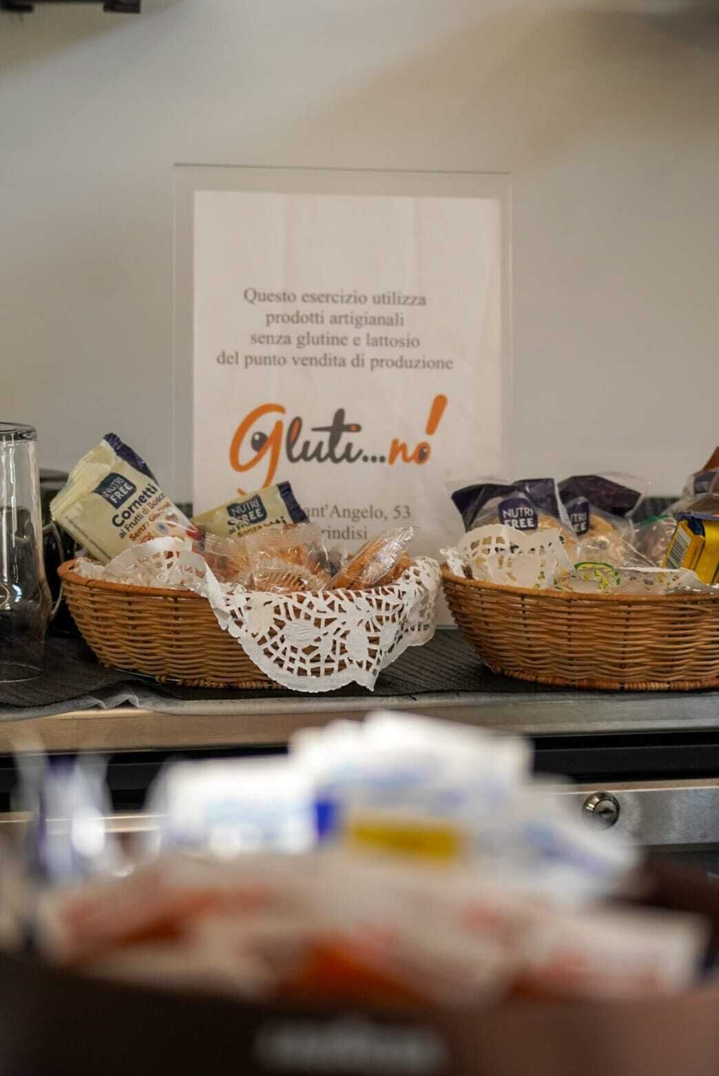 Zona de bufé con cestas de comida y un cartel que indica productos sin gluten.