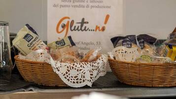 Zona de bufé con cestas de comida y un cartel que indica productos sin gluten.