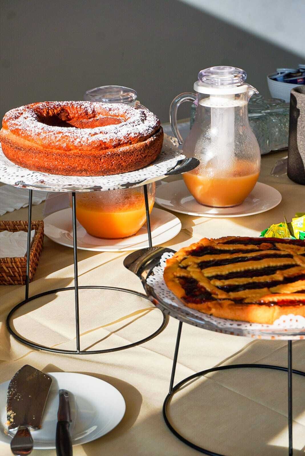 Una mesa con varios postres, como un pastel ring, una tarta y una jarra de jugo de naranja.