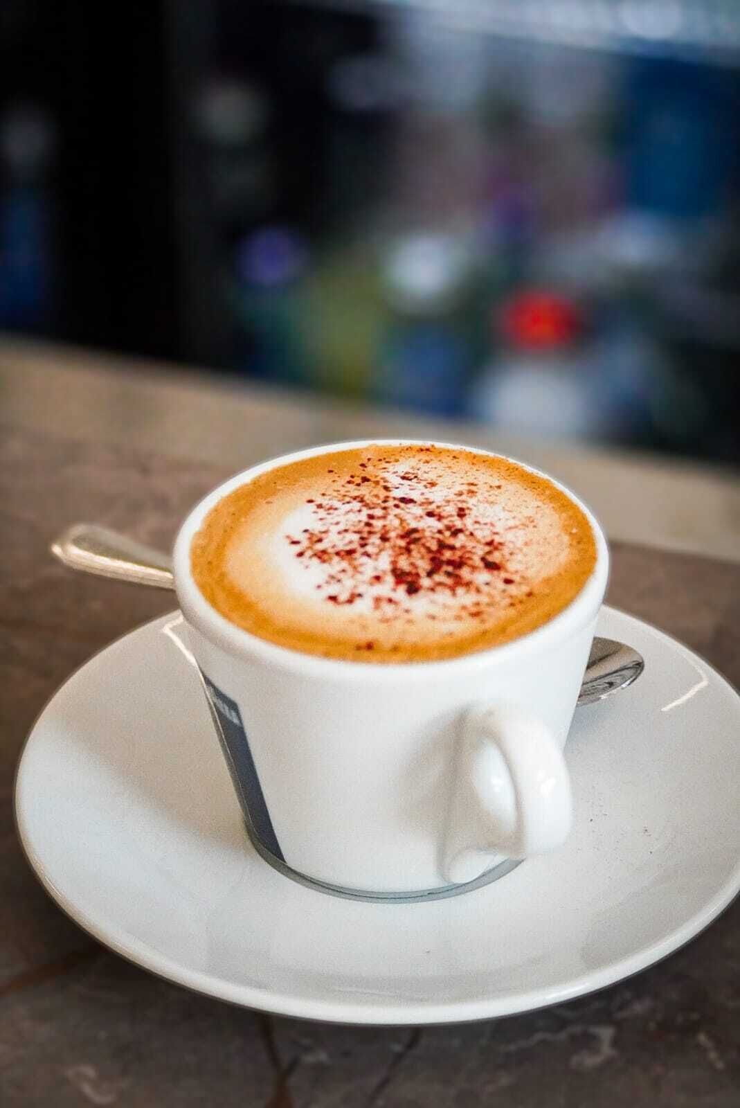 A cup of coffee with a latte art design on a saucer.