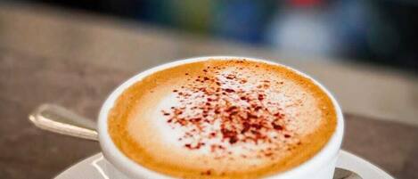 A cup of coffee with a latte art design on a saucer.