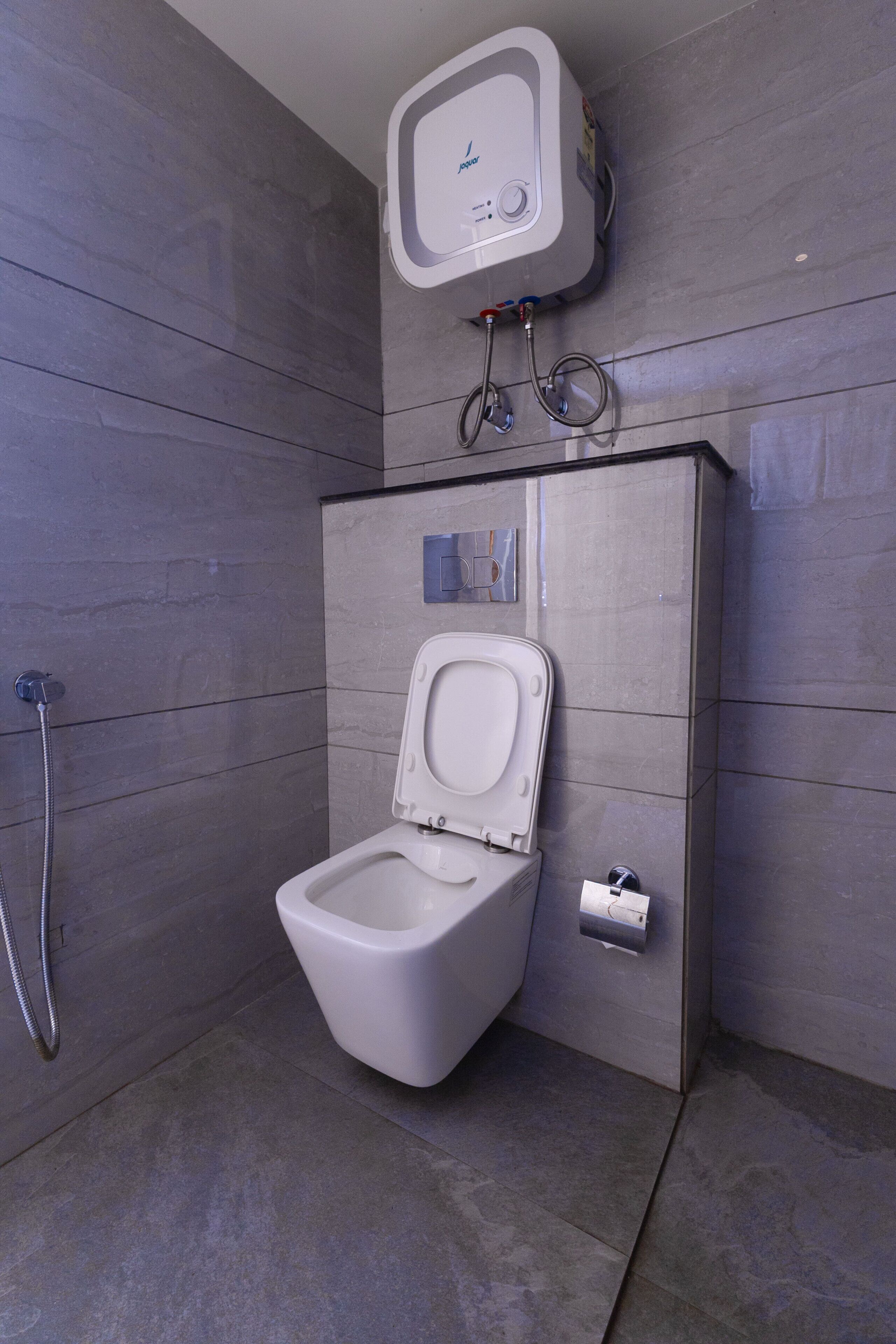 A modern bathroom with a toilet, a shower, and a wall-mounted control panel.