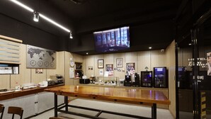 Un vestíbulo de hotel con un mostrador de recepción de madera, zona de estar y una pantalla de televisión que muestra un programa.