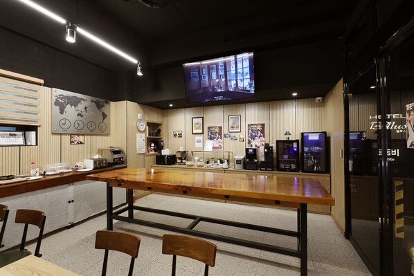 A hotel lobby with a wooden reception desk, seating area, and a television screen displaying a program.