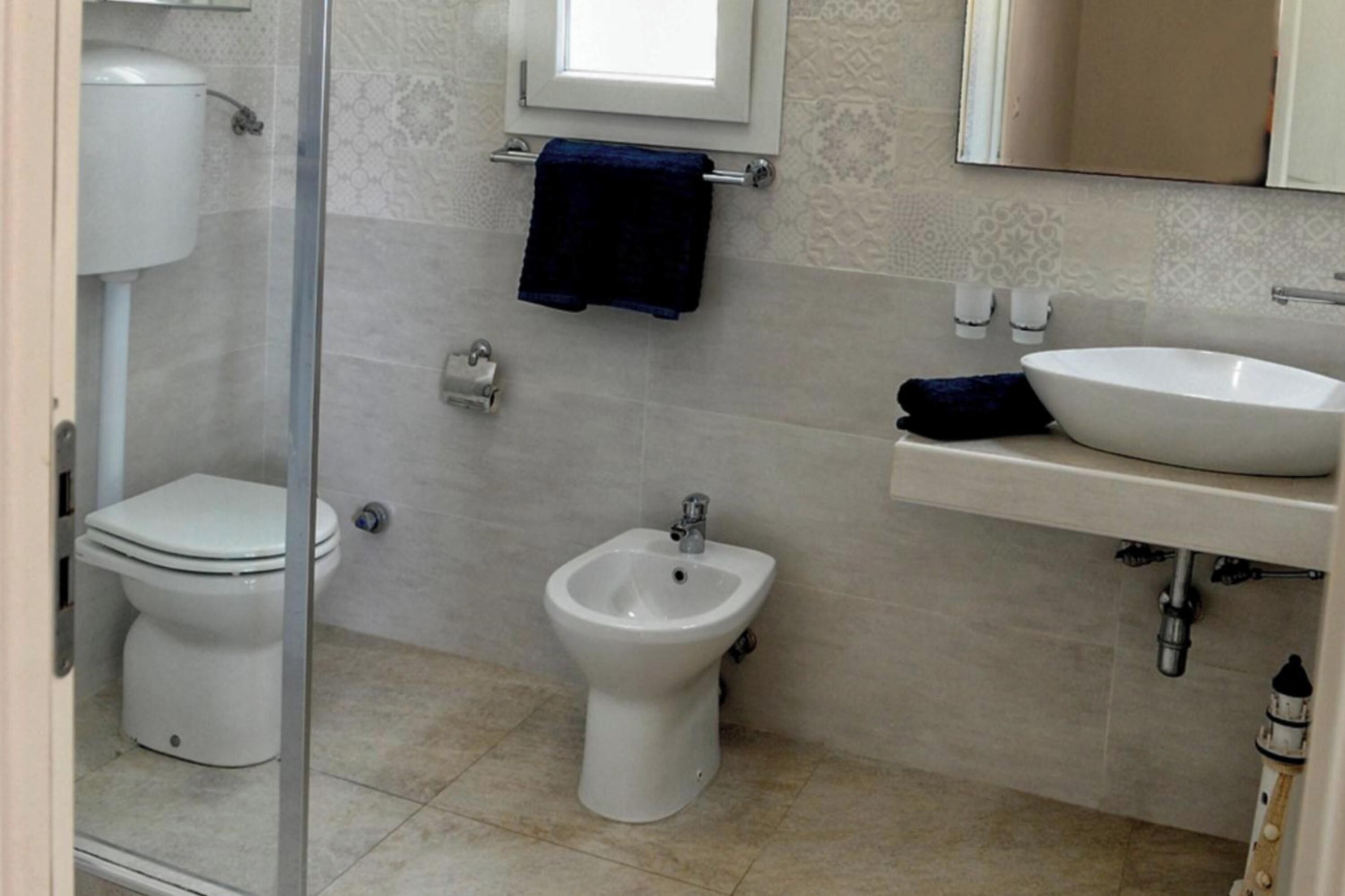 Un baño con inodoro, bidé, lavabo y un espejo sobre el lavabo.