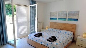 A bedroom with a wooden bed, a sliding glass door, and three paintings on the wall. - Complesso Villa Vanissia (Castrignano del Capo)