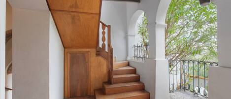 A wooden staircase with a white wall and a metal railing.