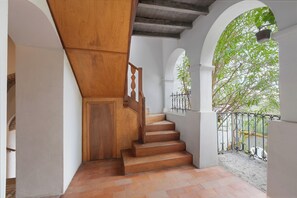 A wooden staircase with a white wall and a metal railing.