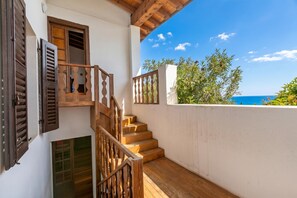 A wooden staircase leading to a balcony with a view of the sea.