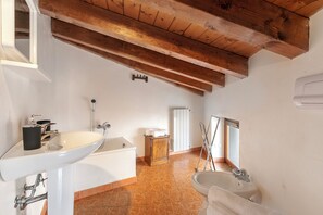 A bathroom with a white sink, bathtub, and a wooden ceiling.